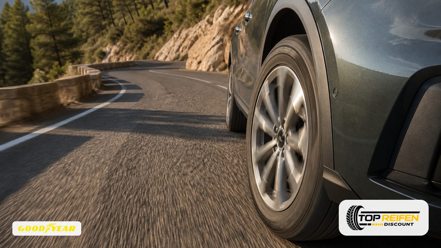 Hochwinkel-Aufnahme eines Fahrzeugs, das eine Sommerbergkurve fährt; Fokus auf den GOODYEAR E-RS-A 235/55 R18 Reifen und seinen Kontakt zur trockenen Straße.